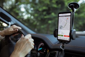 vrouwelijke handen achter het stuur zicht hebbende op een telefoon met navigatie-app